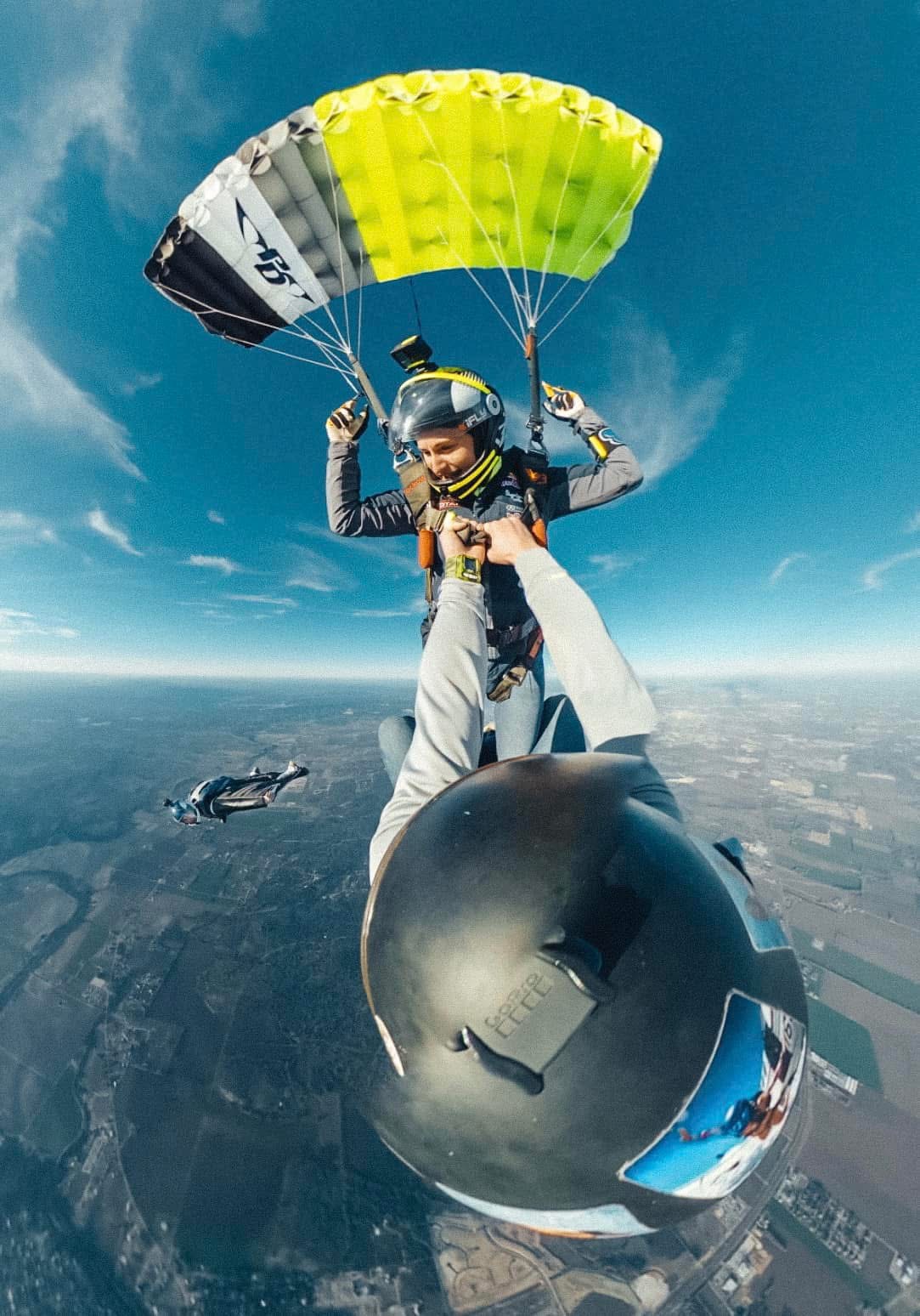 GoPro selfie under neon yellow canopy with another skydiver in freefall